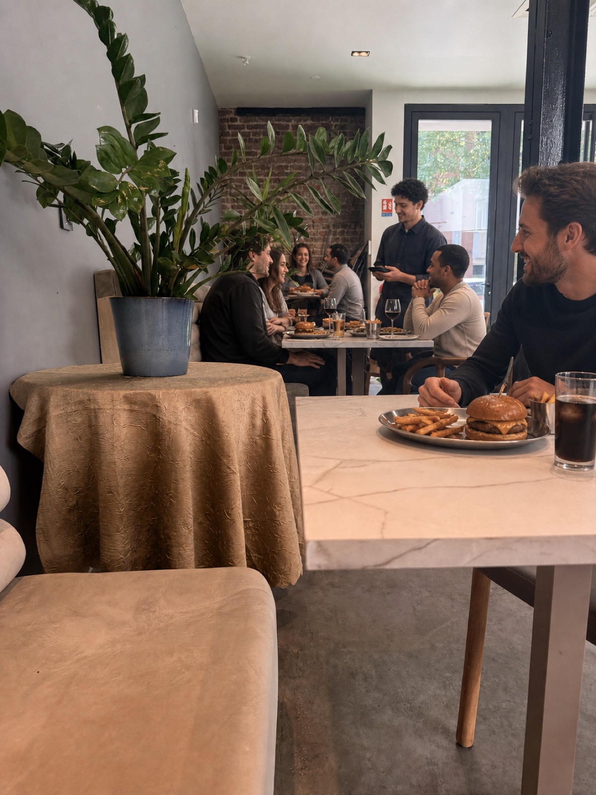 Burger et frites maison servis sur une table en marbre, mur de briques en fond